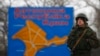 FILE - A Russian serviceman stands on duty near a map of the Crimea region near the city of Kerch, March 4, 2014.