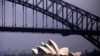 FILE - The sun illuminates the Sydney Opera House as a ferry sails past during a storm at Sydney Harbor in Australia.