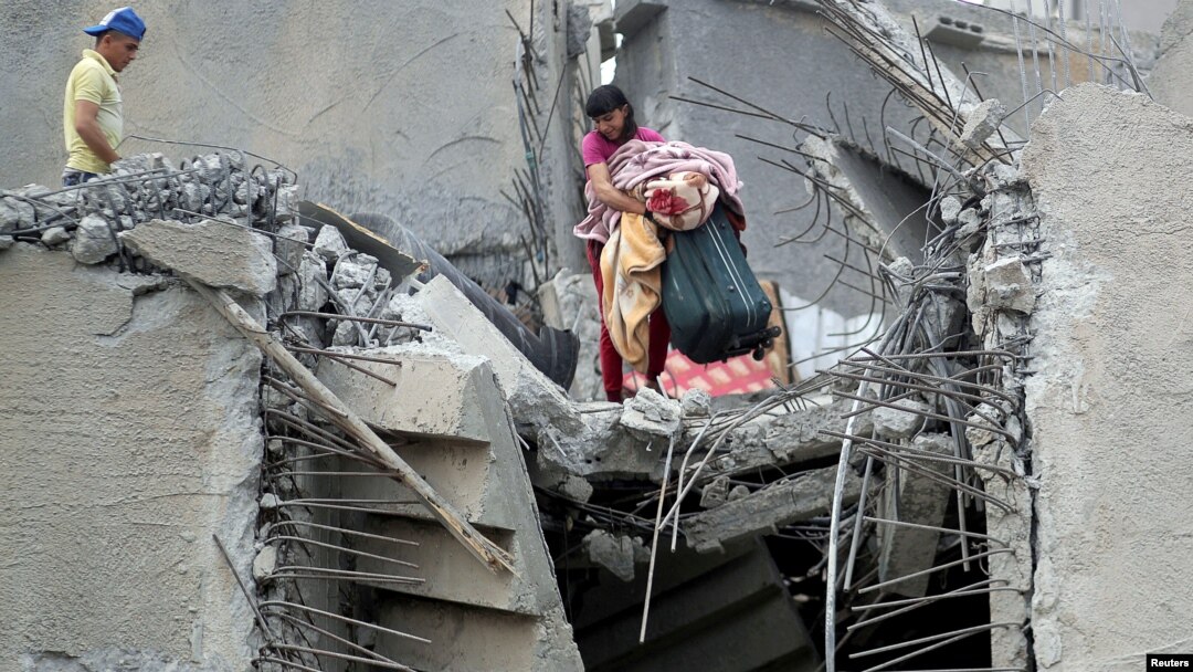 FILE - A Palestinian holds his belongings from the rubble of his house that was destroyed by an Israeli air strike, Gaza City May 7, 2019. 