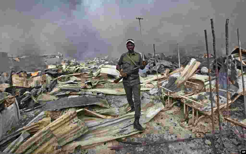 A Somali soldier walks through the wreckage after a fire engulfed the capital's main market in Mogadishu. A police officer said the overnight inferno was moved by winds which started at the gold bazaar and rapidly spread into different areas of the market, razing large buildings, shops and food stores.