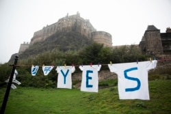 FILE - A Yes campaign sign for the Scottish independence referendum stands backdropped by Edinburgh Castle, in Edinburgh, Scotland, Sept. 18, 2014.