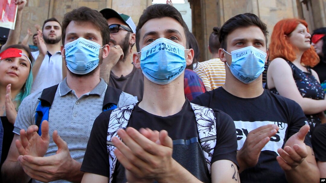 Young opposition demonstrators wearing masks reading "Russia Occupant " gather in front of the Georgian Parliament building in Tbilisi, Georgia, June 21, 2019.