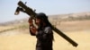 FILE - An Islamist Syrian rebel group Jabhat al-Nusra fighter talks on a walkie-talkie while carrying his weapon in the northern Idlib province May 17, 2014. 