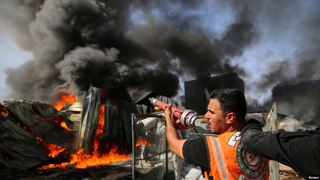 A Palestinian firefighter participates in efforts to put out a fire at a sponge factory after it was hit by Israeli artillery shells, according to witnesses, in the northern Gaza Strip, May 17, 2021.