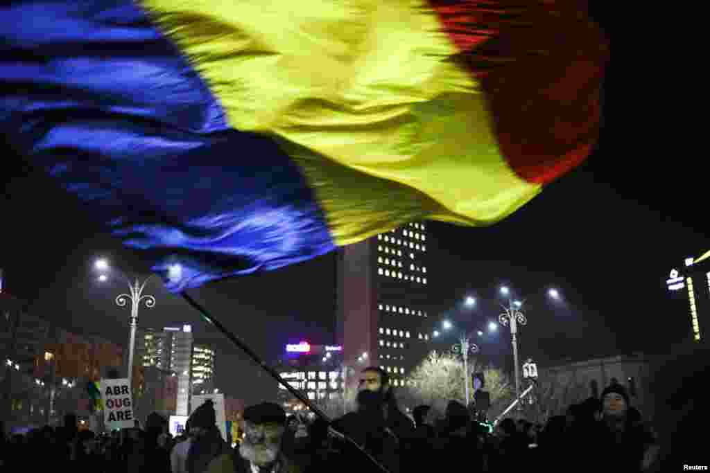 A protester waves a large Romanian national flag during a demonstration in Bucharest, Romania.