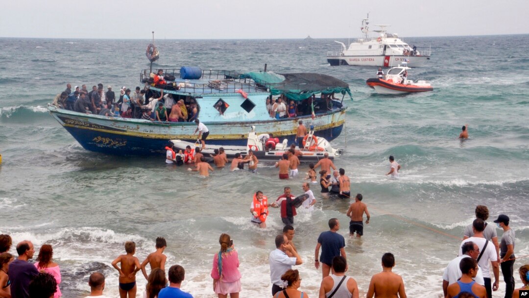 FILE - Vacationers join Italian Coast Guard officers to help migrants from Eritrea ashore near the seaport of Siracusa after a long and treacherous journey, Aug. 15, 2013.