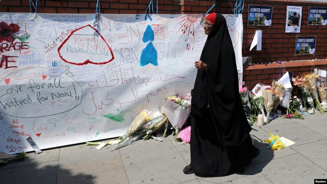 A woman walks past messages attached to a wall near the scene of an attack next to Finsbury Park Mosque, in north London, June 20, 2017. 