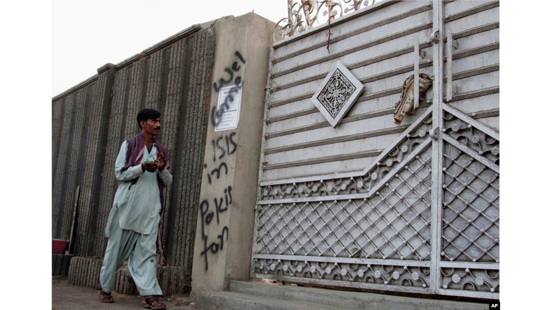 FILE - A man looks at graffiti supporting the Islamic State group as he walks past an entrance of a compound in Karachi, Pakistan, Nov. 12, 2014. Hate roams freely online "while the state chases poets, artists and journalists,” one critic wrote on Twitter.
