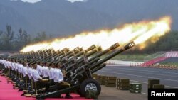 FILE - Paramilitary policemen and members of a gun salute team fire cannons during a training session for a military parade to mark the 70th anniversary of the end of the World War II, at a military base in Beijing, China. China is now the world’s third largest arms exporter behind the U.S. and Russia, and the country accounted for nearly six percent of arms exports between 2011 and 2015.