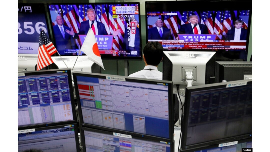 An employee of a foreign exchange trading company looks at monitors showing U.S. President elect Donald Trump speaking on TV news in Tokyo, Japan, Nov. 9, 2016.