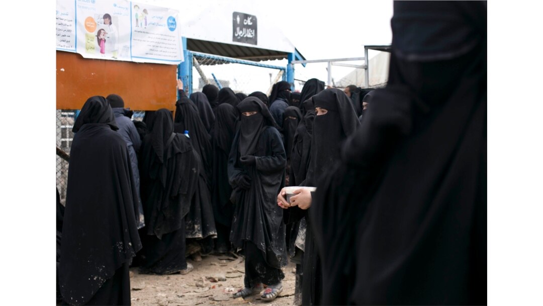 FILE - In this Tuesday, March 10, 2020 file photo, migrants wait in line for a distribution of blankets close to the Turkish-Greek border near Pazarkule, Edirne region, Turkey.