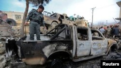 An Afghan policeman inspects a damaged vehicle at the site of a complex suicide attack in Sarobi district, east of Kabul, Feb. 21, 2014.