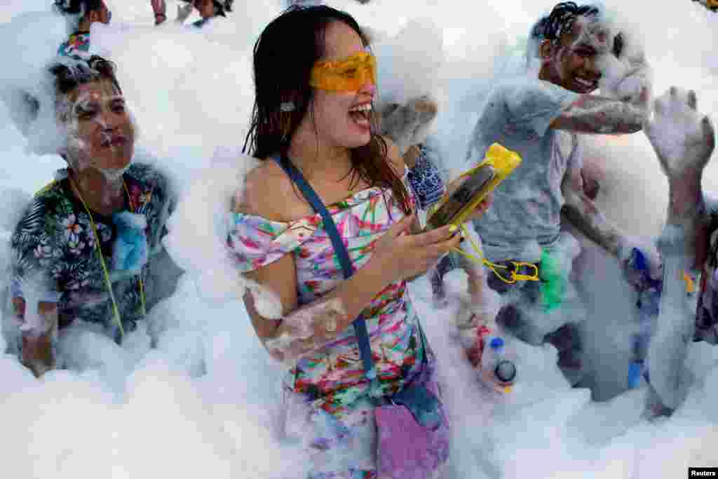 Revelers react at a foam party during Songkran Festival celebrations in Bangkok, Thailand.