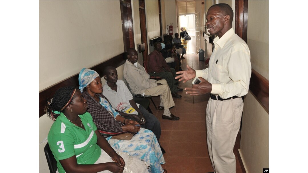 FILE - A health worker from The AIDS Support Organization (TASO) speaks with patients waiting for treatment in Kampala, Uganda, July 12, 2012.