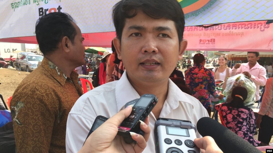 Ung Vuthy, local coordinator for CЕDAC, is seen being interviewed by reporters at the community market in Kompong Speu province. (Photo - Hul Reaksmey/VOA Khmer)