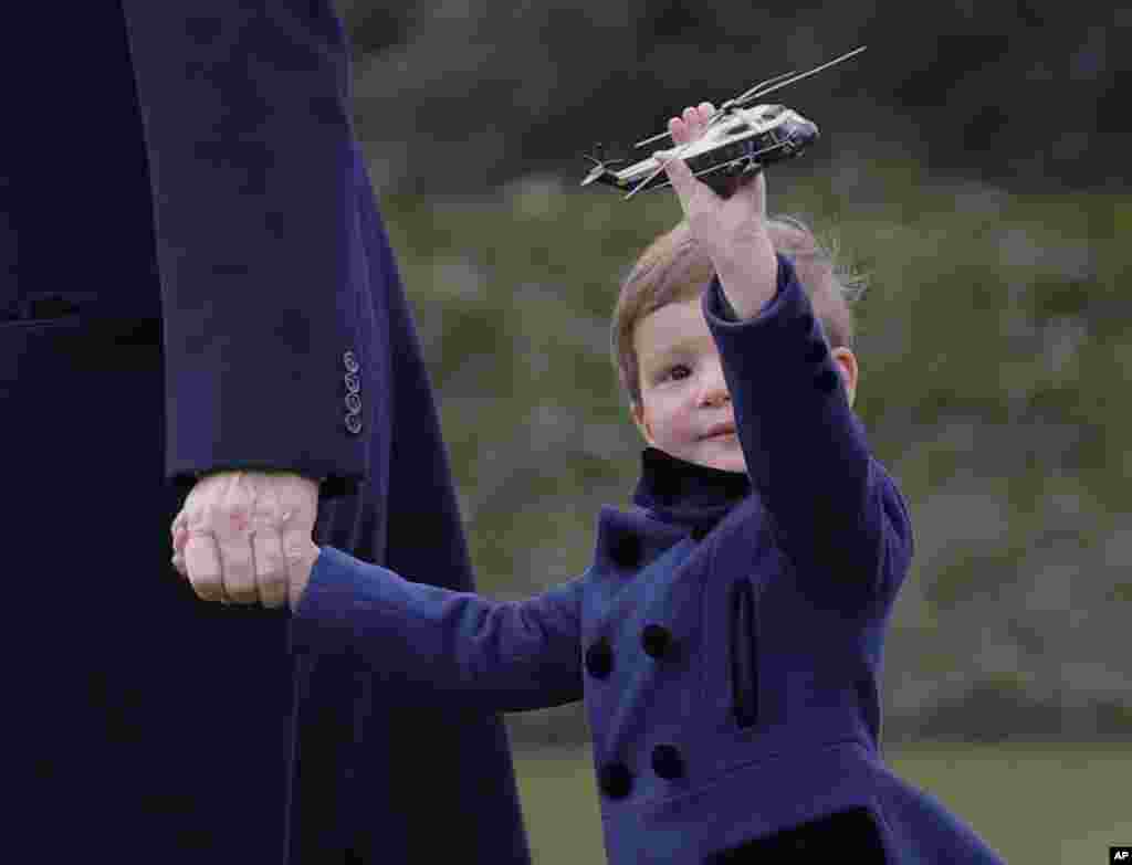 President Donald Trump's grandson Joseph Kushner holds a model of Marine One, as they walk across the South Lawn of the White House in Washington.