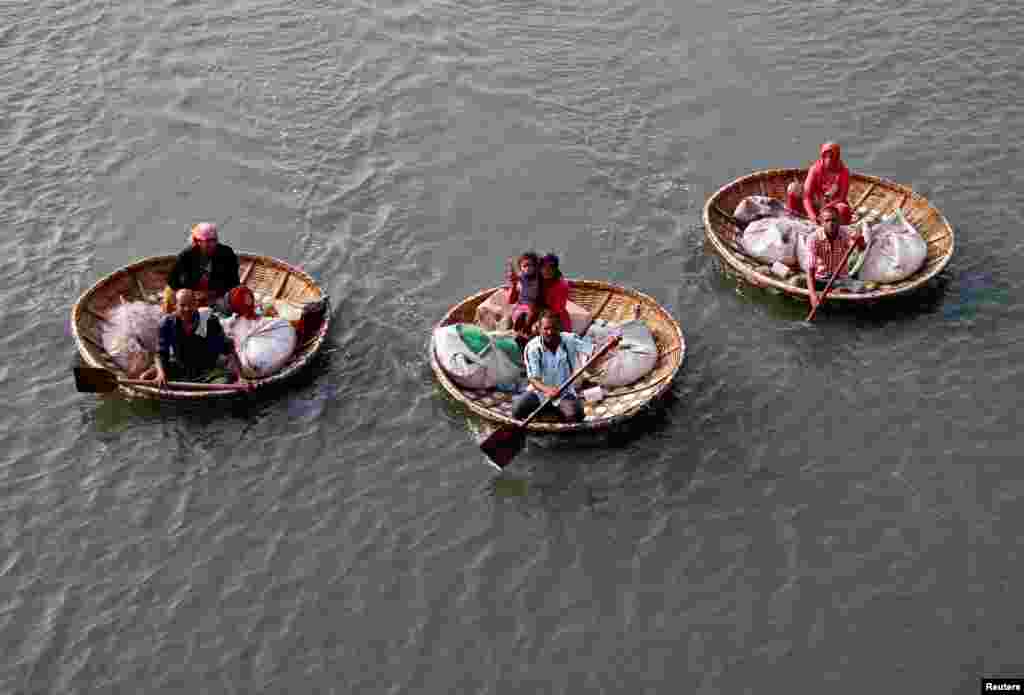 Fishermen paddle their boats as they carry their family members in the waters of Vembanad Lake in Kochi, India.