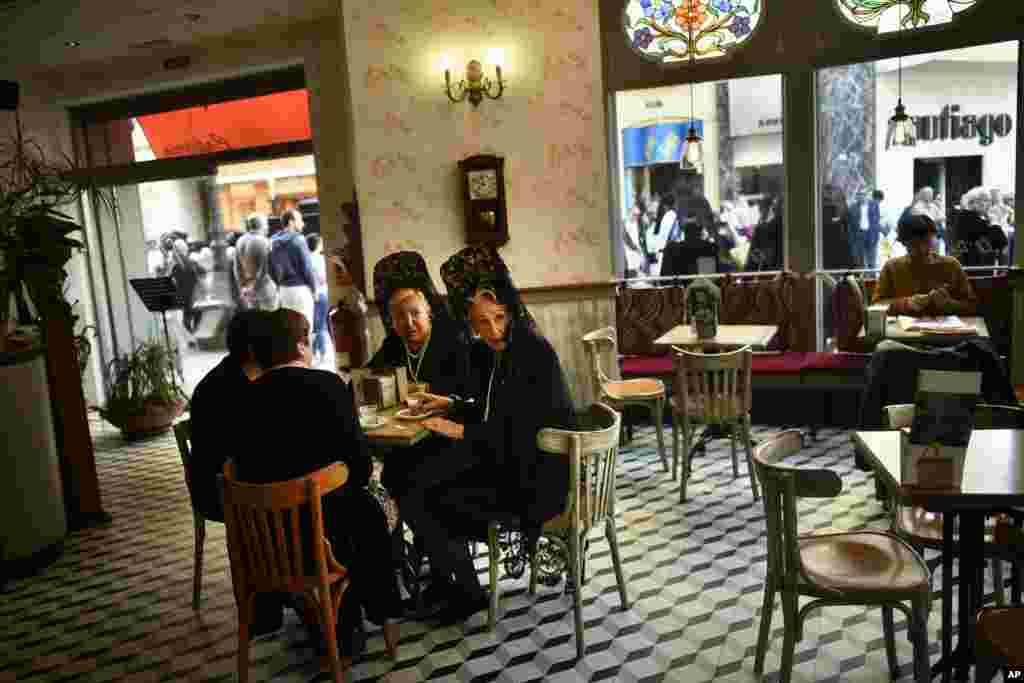 Two female penitents have coffee during the procession of the "Exaltacion de La Santa Cruz" brotherhood, during Holy Week in Zaragoza, northern Spain.