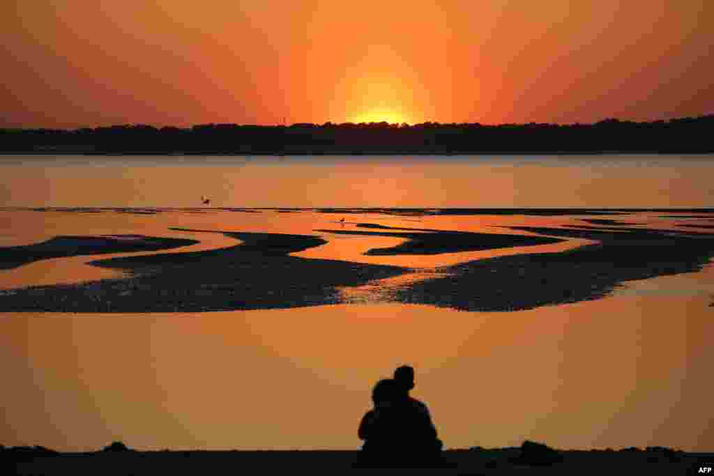 People watch the sunset on the Cap Ferret, from a beach of the Arcachon Bay, France, April 8, 2017.