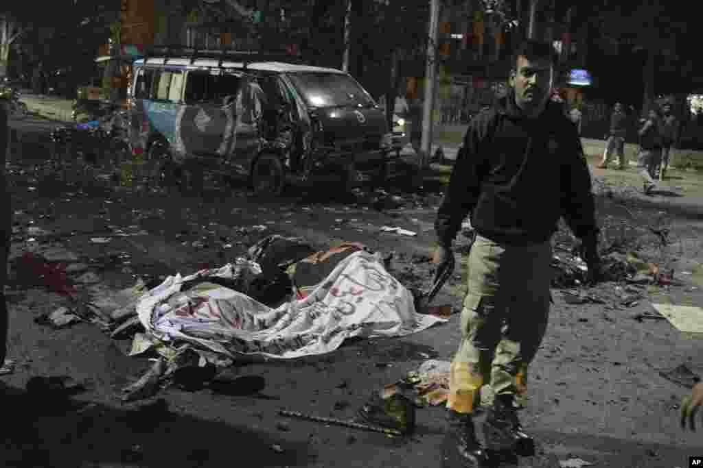 A police commando stands alert at the site of a deadly bombing in Lahore, Pakistan. Police say a large bomb has struck a protest rally, killing many people and wounding others.