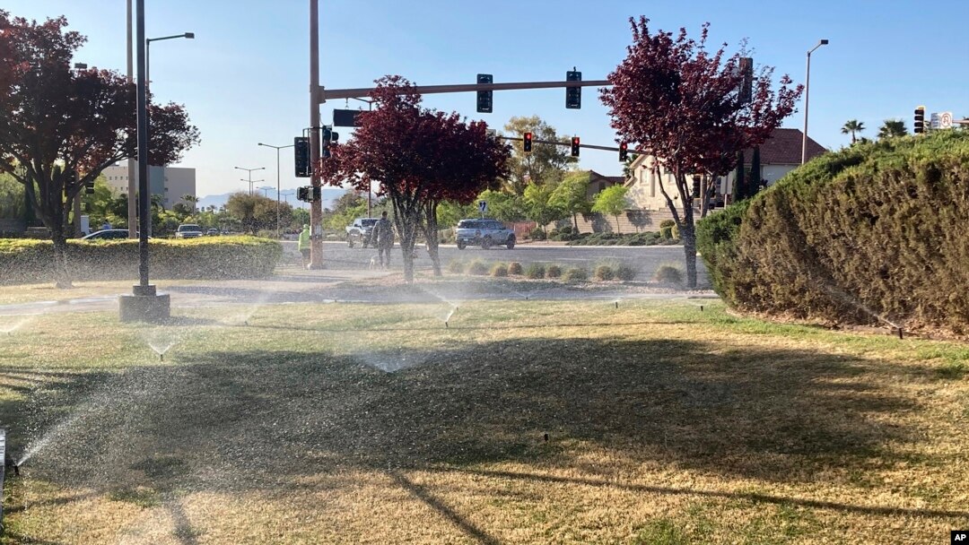 Sprinklers water grass near a street corner Friday, April 9, 2021, in the Summerlin neighborhood of northwest Las Vegas. (AP Photo/Ken Ritter)