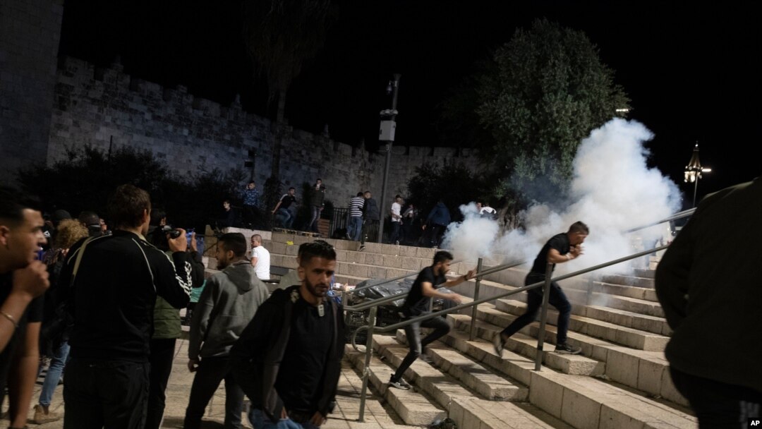 Palestinians react to stun grenades fired by Israeli police to clear the Damascus Gate to the Old City of Jerusalem after clashes at the Al-Aqsa Mosque compound, May 7, 2021.