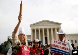 A woman holds up a rolling pin in support of cake artist Jack Phillips while outside of the Supreme Court, Dec. 5, 2017.