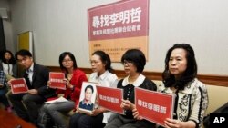 FILE - In this photo taken March 24, 2017, Lee Ching-yu, third from right holds up a photo of her missing husband and Taiwanese pro-democracy activist Lee Ming-che during a press conference with other representatives of non-governmental organizations calling for help to find his whereabouts in Taipei, Taiwan.