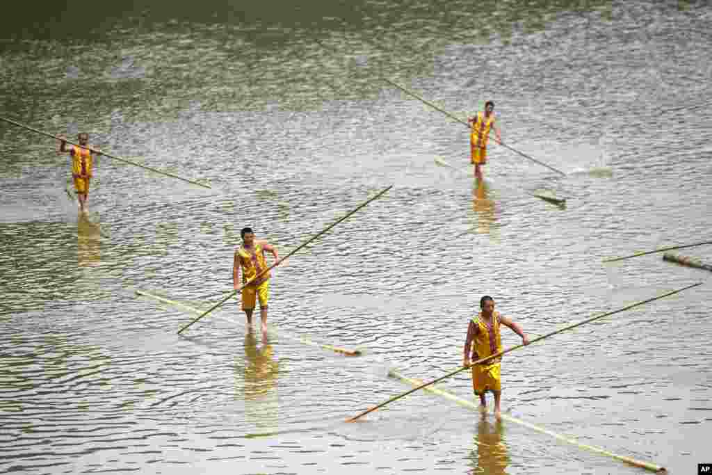 Participants paddle on bamboo poles in a performance ahead of the Dragon Boat festival at Tanghe Town in Chongqing, China, May 27, 2017.