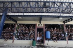 Imprisoned gang members, wearing protective face masks, look out from behind bars during a media tour of the prison in Quezaltepeque, El Salvador, Sept. 4, 2020.