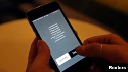 A Vodafone employee shows M-Pesa's text message transactions option on a mobile phone, in Bucharest, April 2014.