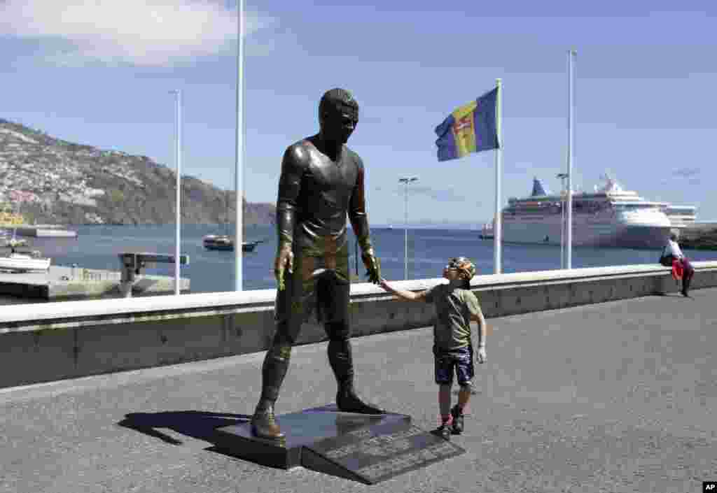 A child touches a statue of Portuguese star soccer player Cristiano Ronaldo in Funchal, the capital of Madeira island.