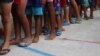 FILE - Venezuelan migrant children line up inside a coliseum where a temporary camp has been set up, after fleeing their country due to military operations, according to the Colombian migration agency, in Arauquita, Colombia, March 26, 2021.