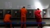 FILE - Detainees talk on telephones at the Adelanto ICE Processing Center in Adelanto, Calif., Aug. 28, 2019. 