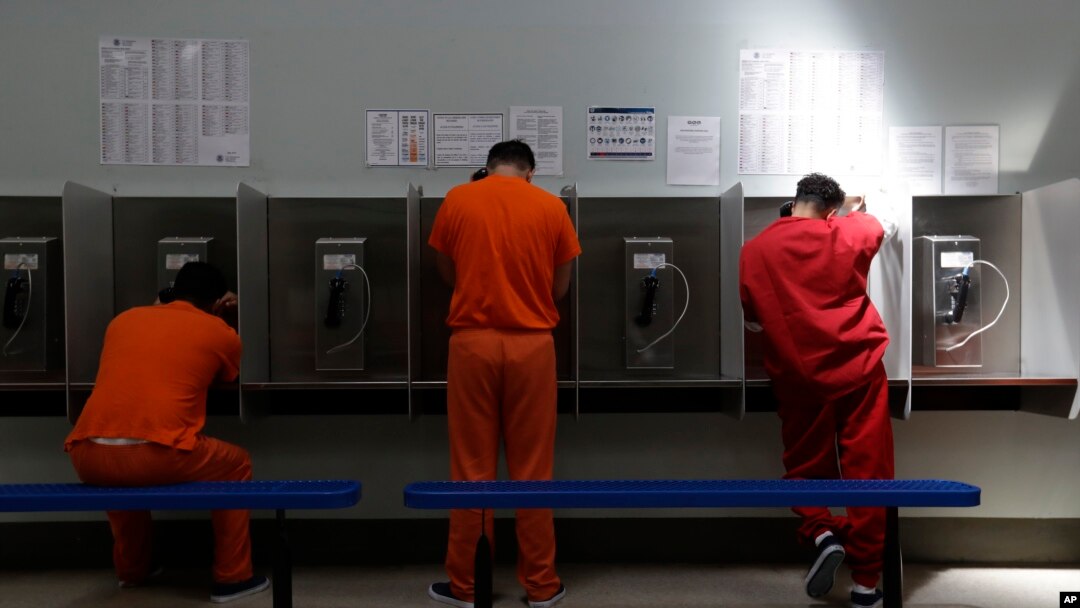 FILE - Detainees talk on telephones at the Adelanto ICE Processing Center in Adelanto, Calif., Aug. 28, 2019. 
