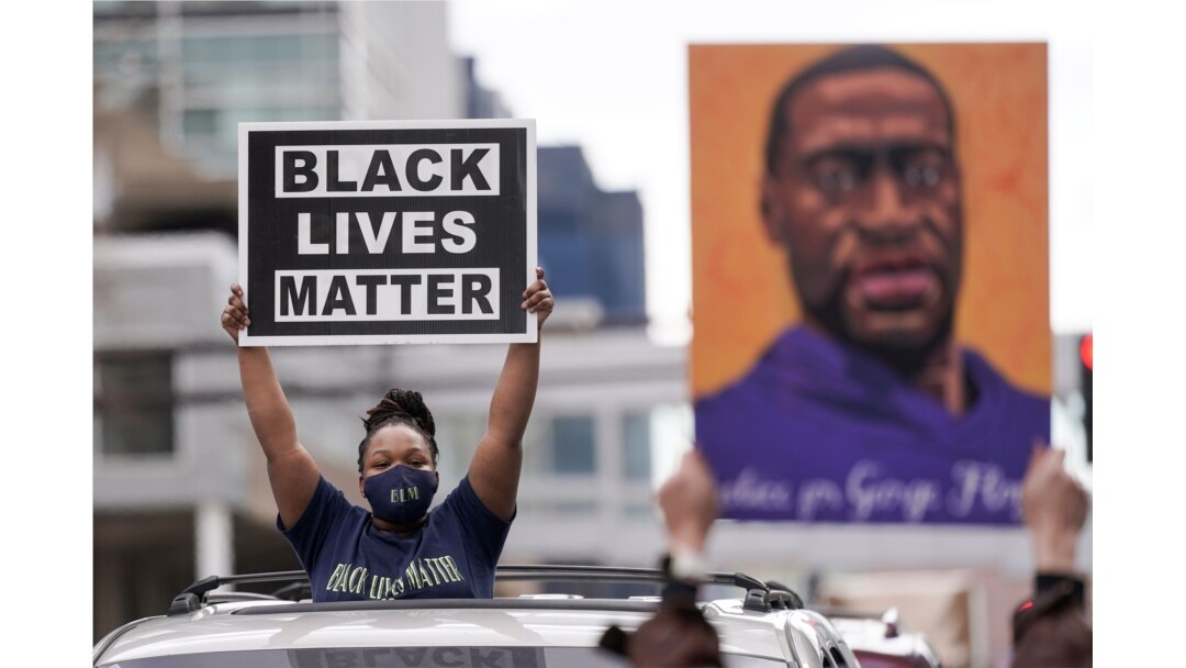 FILE - People hold up signs, including one with an image of George Floyd, outside the courthouse in Minneapolis, Minnesota, April 20, 2021, after former Minneapolis police officer Derek Chauvin was found guilty in the death of Floyd.