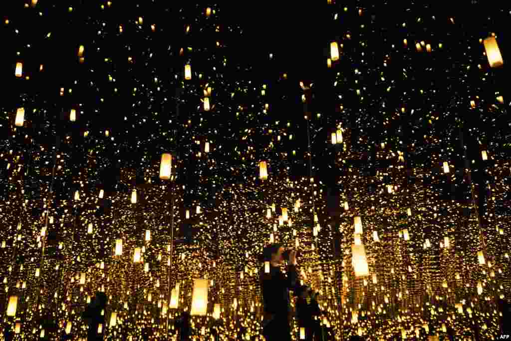A woman photographs inside the Aftermath of Obliteration of Eternity room during a preview of the Yayoi Kusama's Infinity Mirrors exhibit at the Hirshhorn Museum in Washington, D.C., Feb. 21, 2017.