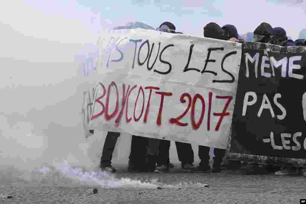 Youths shield behind a banner as Paris police are firing tear gas, during the May Day demonstration in Paris, France.