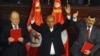 Assembly speaker Mustapha Ben Jaafar, left, Tunisian President, Moncef Marzouki, center, and outgoing prime minister Ali Larayedh gesture after signing the new constitution into law in Tunis, Jan.27, 2014. 