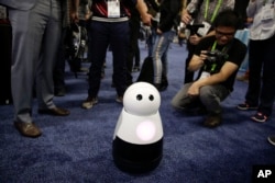 FILE - Mayfield Robotics' Kuri home robot is surrounded by attendees during CES Unveiled at CES International in Las Vegas, Jan. 7, 2018.