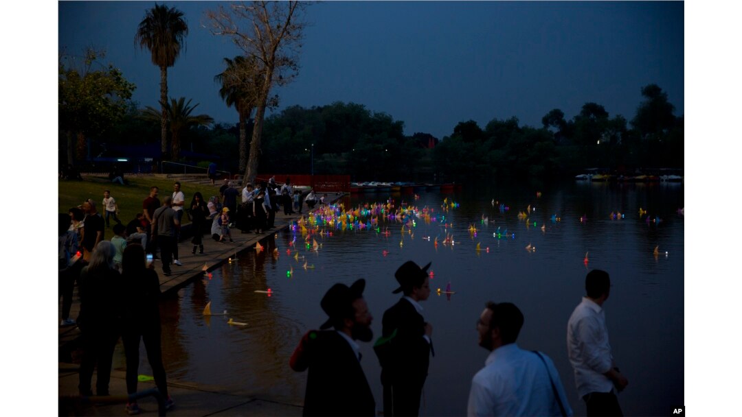 People look upon floating handmade boats with the names of Nazi concentration camps, during a ceremony marking the annual Holocaust Remembrance Day in Hayarkon park in Tel Aviv, Israel, May 1, 2019.