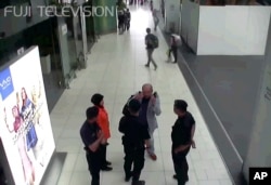 FILE - Kim Jong Nam, exiled half brother of North Korea's leader Kim Jong Un, gestures toward his face while talking to airport security and officials at Kuala Lumpur International Airport, Malaysia.