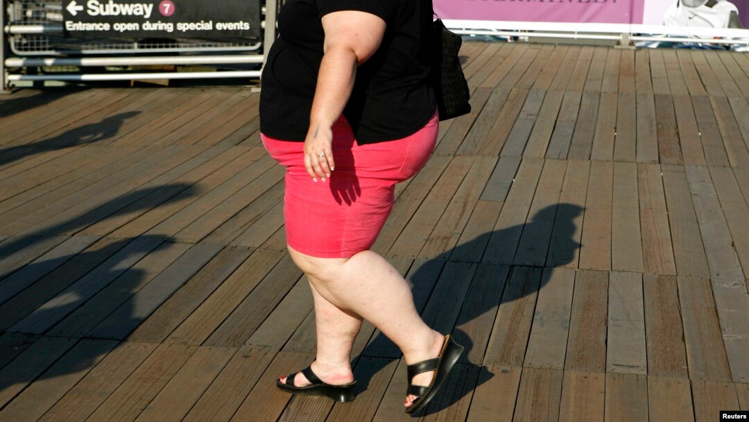 FILE - A woman walks along a boardwalk in New York. The WHO recommends people keep their sugar intake at below 10 percent of their total energy needs.