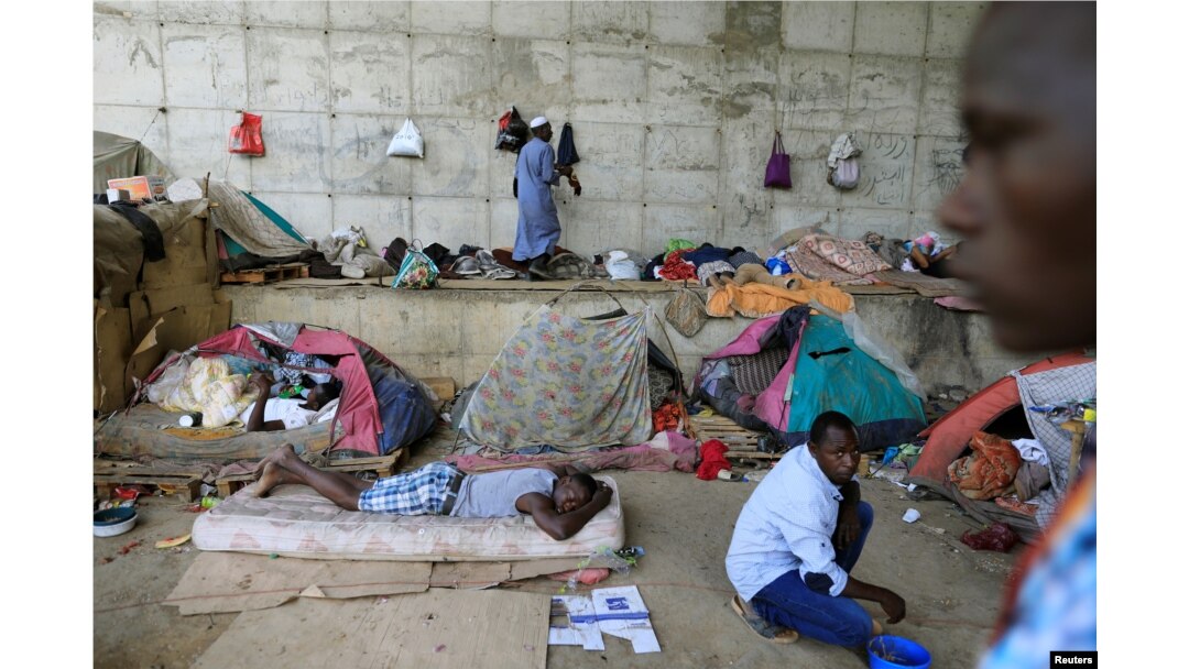 FILE - African migrants take shelter under the bridge of a motorway on the outskirts of Algiers, Algeria, June 28, 2017.