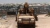 Kenya Defence Force (KDF) soldiers, serving in African Union Mission in Somalia (AMISOM), patrol past stockpiles of charcoal near the Kismayo sea port town (2013 photo)