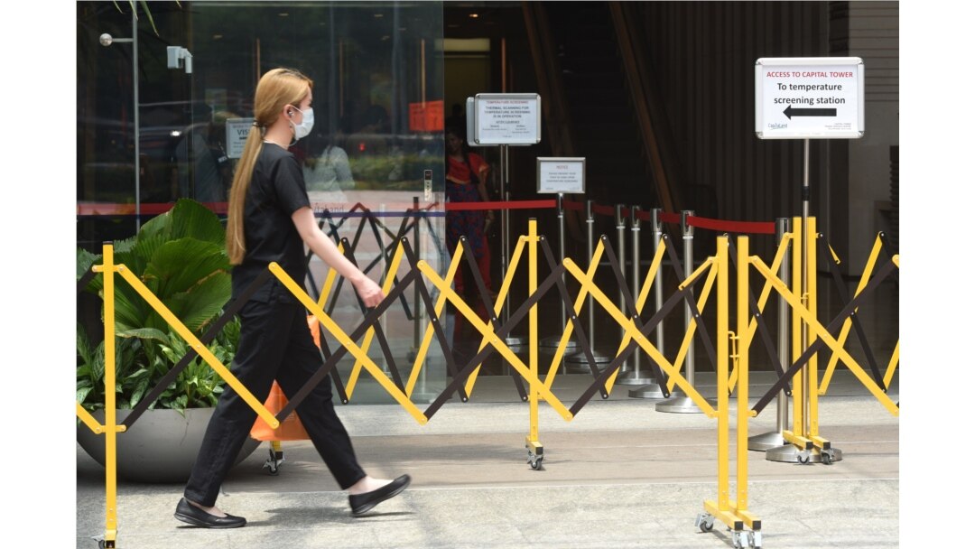 A woman wearing a face mask approaches a temperature screening area of an office building as a preventive measure against the coronavirus spread, in Singapore, March 20, 2020.