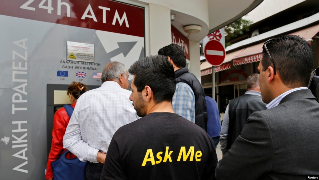 A man makes a transaction at an ATM outside a branch of Laiki Bank in Nicosia, March 21, 2013.