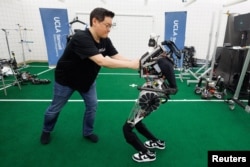 Dennis Hong a professor of Mechanical & Aerospace Engineering at UCLA Samueli School of Engineering attempts to impede the movement of ARTEMIS, a full-sized humanoid robot with first-of-its-kind technology in Los Angeles, California, U.S., April 13, 2023.