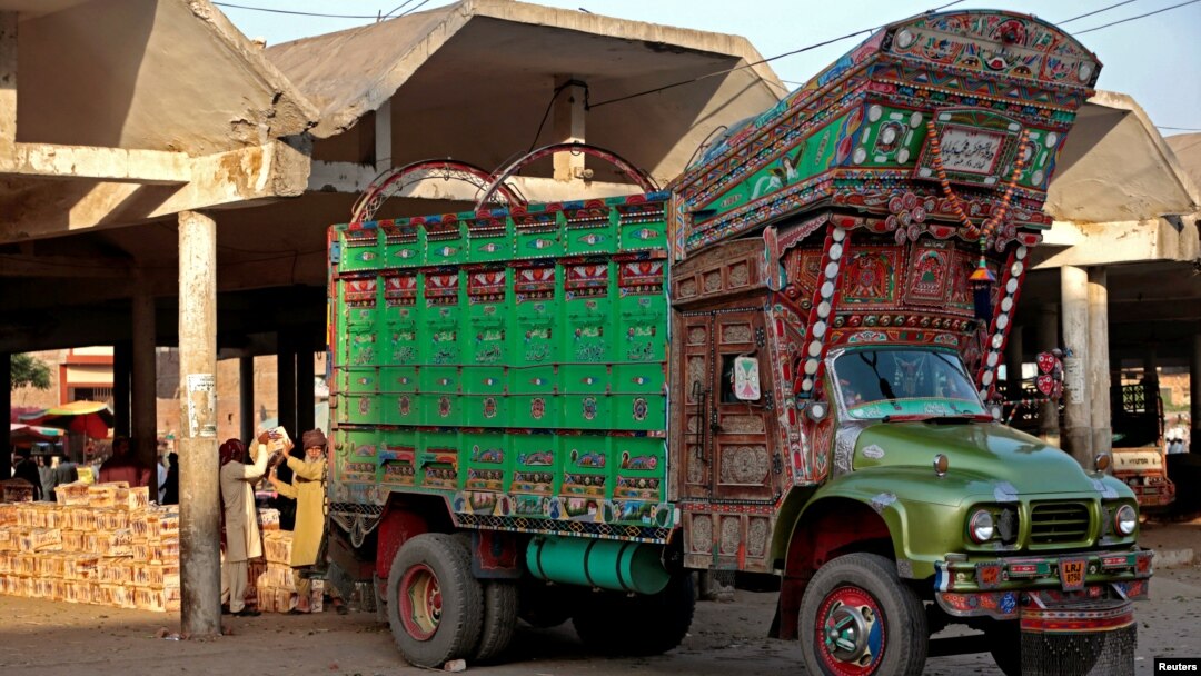 Workers unload fruit from a decorated truck at the wholesale produce market in Faisalabad, Pakistan, May 4, 2017.