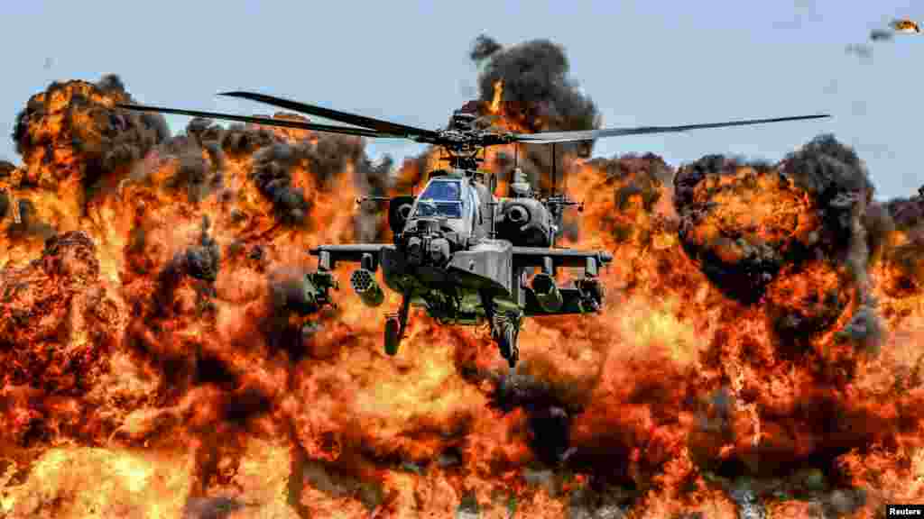 An AH-64D Apache attack helicopter flies in front of a wall of fire during the South Carolina National Guard Air and Ground Expo at McEntire Joint National Guard Base.